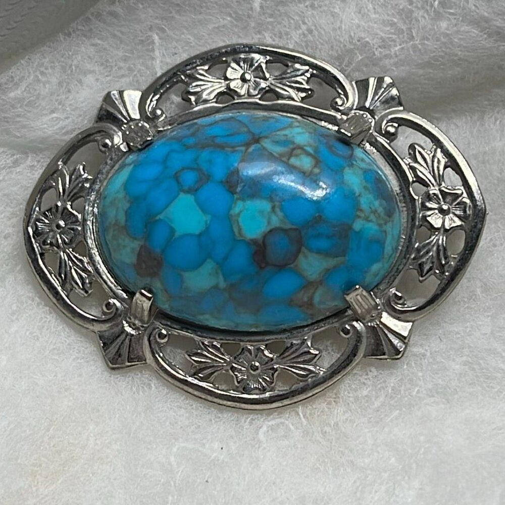 Vintage faux turquoise cabochon set in silver-tone filigree frame.